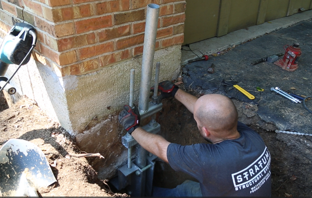 worker performing pier installation on a residential foundation